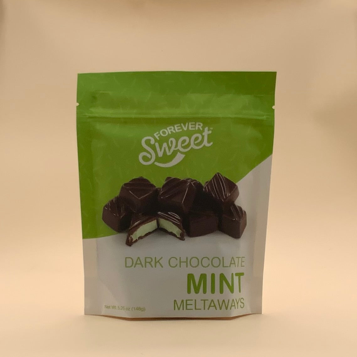 A stand-up pouch of Forever Sweet Dark Chocolate Mint Meltaways on a plain beige background.