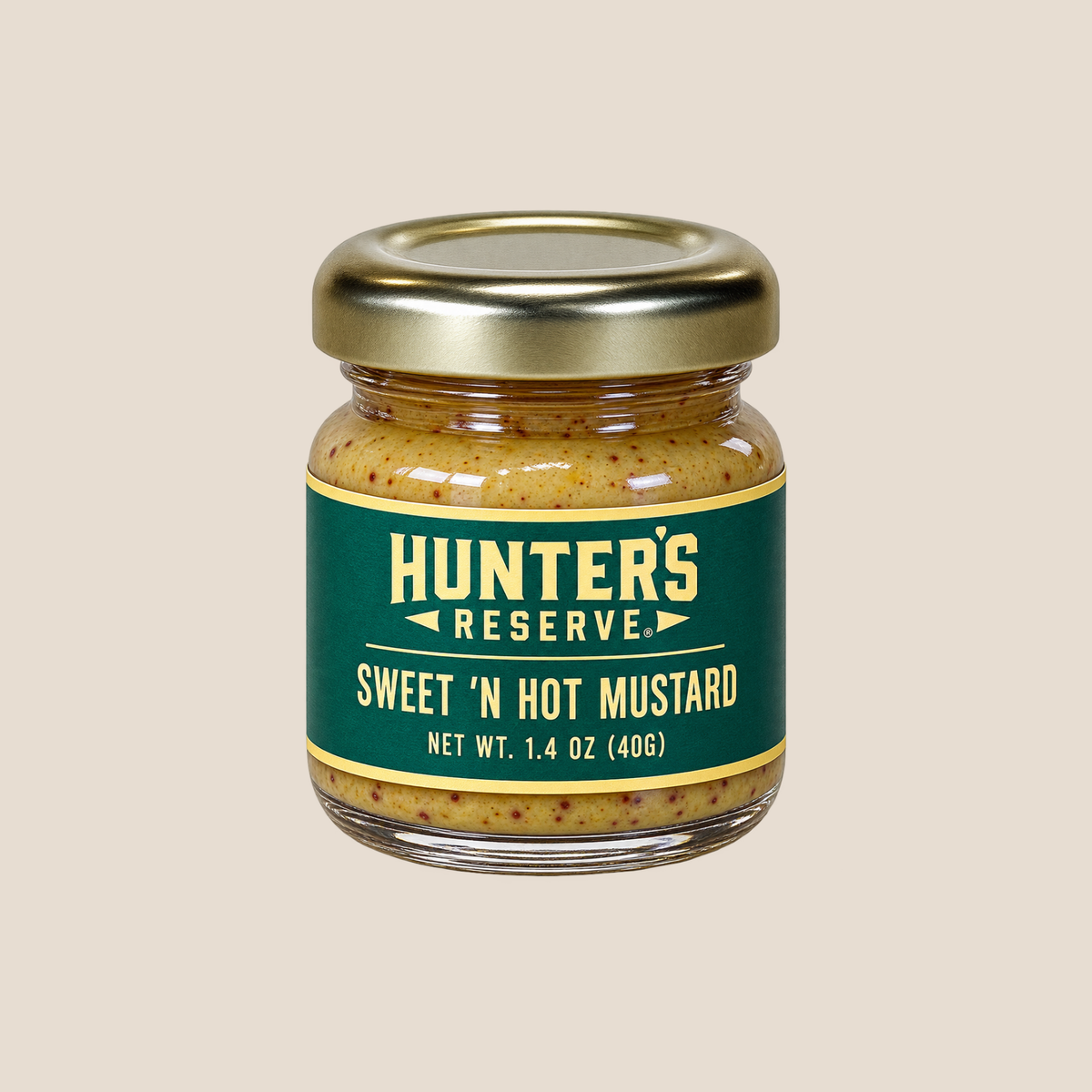 A small glass jar of Hunter's Reserve Sweet 'N Hot Mustard with a gold metal lid and a dark green label, centered on a solid beige background.