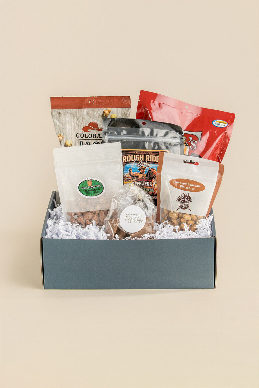 Gift box with various snacks and treats on a beige background