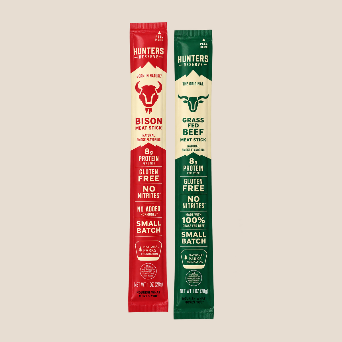 Two vertical packet-style sticks of Hunters Reserve beef jerky shown on a plain warm beige background. The left packet is red and labeled Bison Meat Stick, and the right packet is green and labeled Grass Feed Beef.